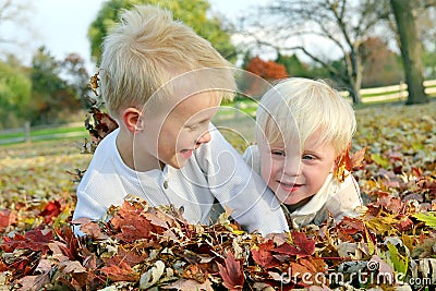 Two Young Children Playing in Fall Leaf Pile Stock Photo