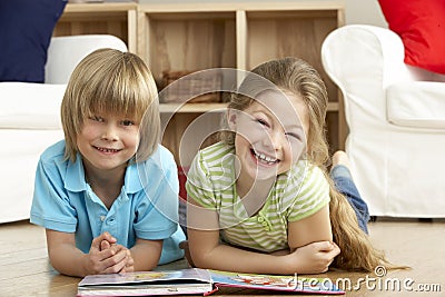 Two Young Children Reading Book at Home Stock Photo