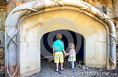 Two young children regard a cave opening at a public garden Stock Photo