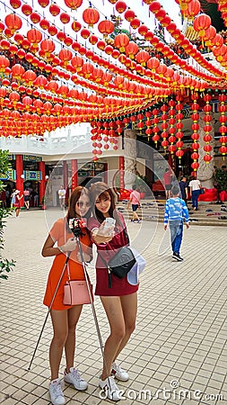 Two young Chinese girls take pictures in a traditional Chinese temple. New Years celebration Editorial Stock Photo