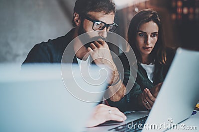 Two young coworkers working together on laptops at modern coworking studio at night.Man wearing glasses using laptop Stock Photo