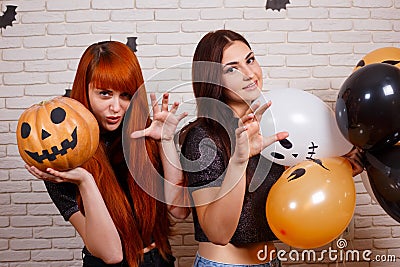 Two young cute women with pumpkin and painted balloons frighten Stock Photo