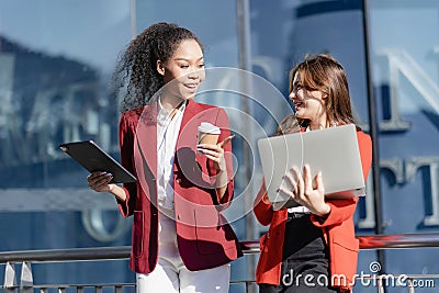 Two young female accountants walk and talk in front of the building's office. Stock Photo