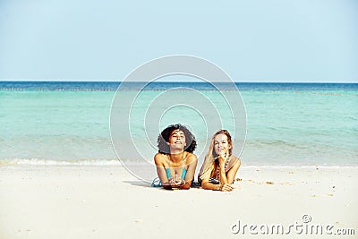 Two smiling women in bikinis suntanning on a tropical beach Stock Photo