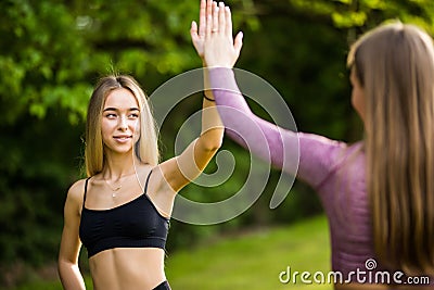 Two young fit sportswomen giving high-five while working in green park Stock Photo