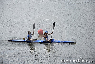 Two young girl athletes are sailing canoe on river, controlling oars. Active outdoor sports training. Side view. Copy space. Editorial Stock Photo