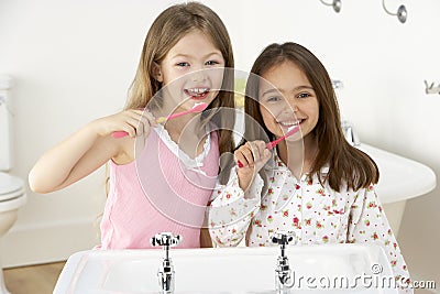 Two Young Girls Brushing Teeth at Sink Stock Photo
