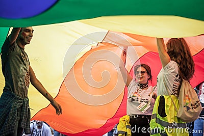 Two young girls and a man standing under a giant rainbow gay flag during the Belgrade Gay Pride. Editorial Stock Photo