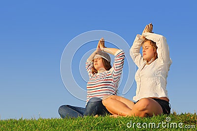 Two young girls meditate at green grass Stock Photo