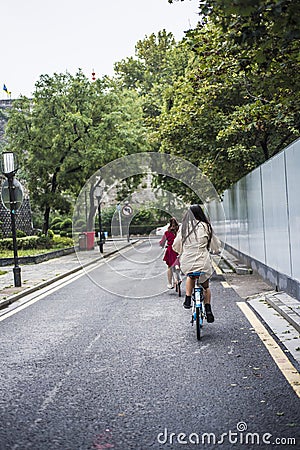 Two young girls riding bicycles leisurely along the ancient city wall Editorial Stock Photo