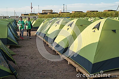 Two young girls are walking along the tent camp Editorial Stock Photo