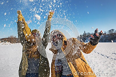 Two young happy people throwing snow and having fun. Selective f Stock Photo