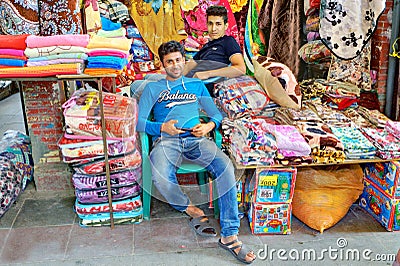 Two young Iranian traders trade textiles in the Grand Bazaar. Editorial Stock Photo