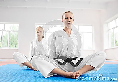Two young karate girl sittting in lotus position after training in light gym. Stock Photo