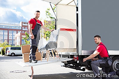 Male Movers Loading Cardboard Boxes In Truck On Street Stock Photo