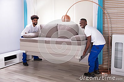 Two Male Movers Placing The Sofa Stock Photo