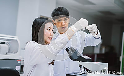 Two young medical scientist looking at test tube in medical laboratory , select focus on male scientist Stock Photo