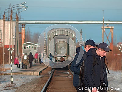 Two young men crossing railway tracks with a train standing in the distance Editorial Stock Photo