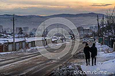Two men going down the hill along the road along the residential neighborhood and the old wooden buildings in Ulan-Ude. Editorial Stock Photo