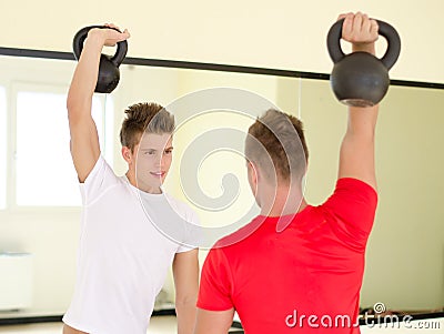 Two young men in gym working out with kettlebells Stock Photo