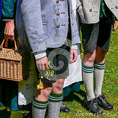 Two Young Men and a Woman wearing German traditional Bavarian clothing, standing in a sunny day. No faces Editorial Stock Photo