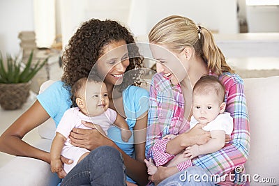 Two Young Mothers On Sofa At Home Stock Photo