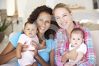 Two Young Mothers On Sofa At Home Stock Photo