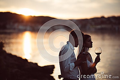 Two young people enjoying a glass of red wine in the sunset on the seaside.Healthy glass od homemade red wine,Mediterranean Stock Photo