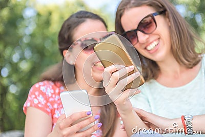 Two young persons looking at smartphone sharing and enjoying social media concept of lifestyle sharing having fun outdoors Stock Photo
