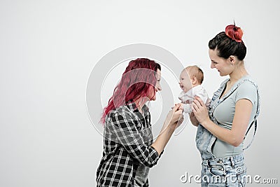 Two young women with a baby on a white background. Same-sex marriage and adoption, homosexual lesbian couple. Stock Photo
