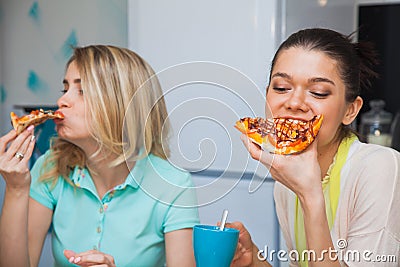 Two young women eat pizza. Girls taste italian traditional food Stock Photo