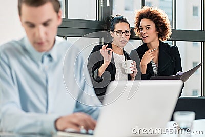 Two young women laughing behind their male colleague Stock Photo