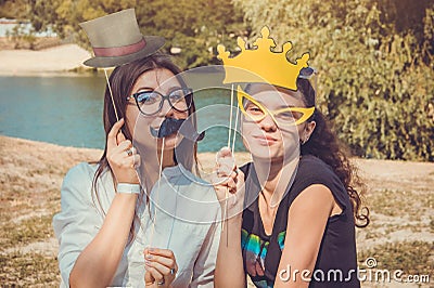 Two young women posing using photo booth props Stock Photo