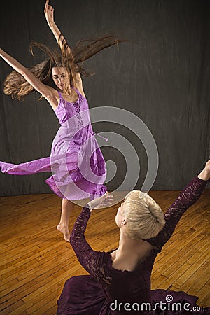 Pair of young women in dresses dancing in the studio. Stock Photo