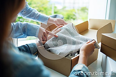 Women receiving and opening a postal parcel box of clothing at home for delivery and online shopping concept Stock Photo