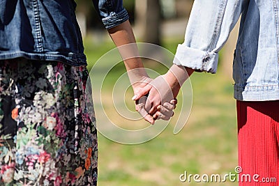 Two young women in walking holding her hands in urban park. Stock Photo