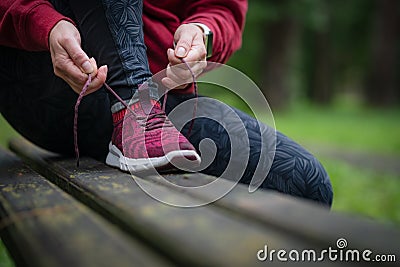 Tying sports shoe. Female athlete getting ready for athletic and fitness training outdoors Stock Photo