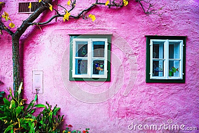 Typical Austrian Alpine houses. Tree in autumn against pink wal Stock Photo