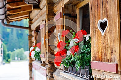 Typical bavarian or austrian wooden window with red geranium flowers on house in Austria or Germany Stock Photo