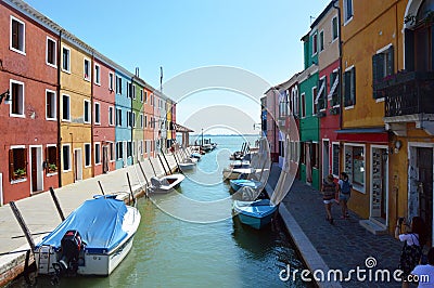 Typical brightly colored houses and narrow channels with tourists in Burano, Venice, Italy. Editorial Stock Photo