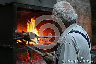 A typical Italian village. Gray-haired old man lights a fire in the oven Editorial Stock Photo