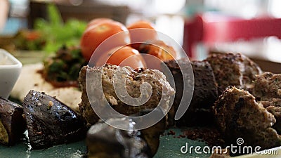 Typical Lebanese dish based on pieces of meat is roasted minced meat with a side of cooked tomatoes Stock Photo