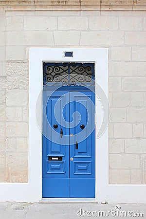 Typical Maltese blue wooden old door on the limestone wall. Malta. Stock Photo