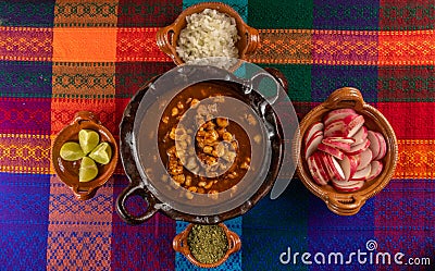 Typical Mexican dish, red Pozole with pork, and with the additional ingredients to put it, such as onion, oregano, radish, lemon 2 Stock Photo