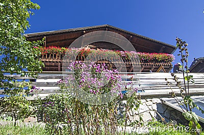 Typical mountain building in stone, white plaster and wood and with colorful flowers Stock Photo