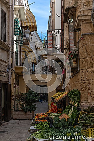 typical narrow alley in the old historic center of Bari Vecchio with a vegetable and fruit stall on the corner Editorial Stock Photo