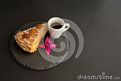 A typical Portuguese cake made of cookies called Bolo de Bolasa with cream, pecans, black and white chocolate on a black slate Stock Photo