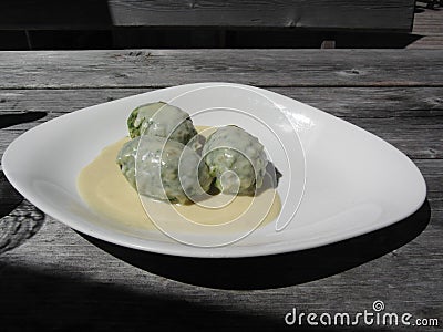 Typical South Tyrolean dish of canederli pasta with cheese sauce on rustic outdoor wooden table at summer Stock Photo