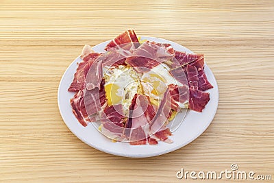 Typical spanish dish of broken eggs with serrano ham on a portion of fried potatoes Stock Photo