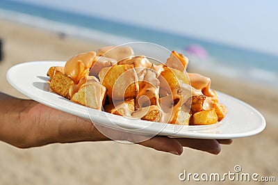 typical spanish patatas bravas, fried potatoes with a hot sauce, on the beach Stock Photo